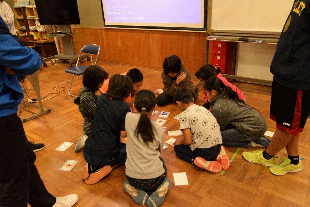 (写真3) かるた取りをする母島小学校の児童。真剣に絵札を見つめ、田崎が札を読むのを待っている。